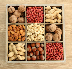 assortment of tasty nuts in  wooden box on table
