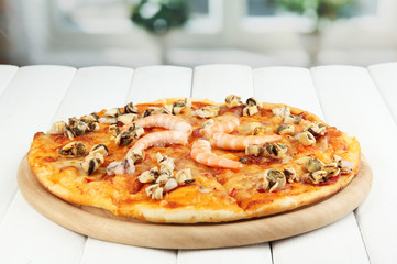 Delicious pizza with seafood on table on bright background