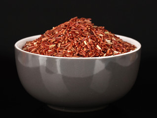 Red rice in gray bowl isolated on black