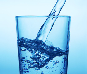 Pouring water into glass isolated on white