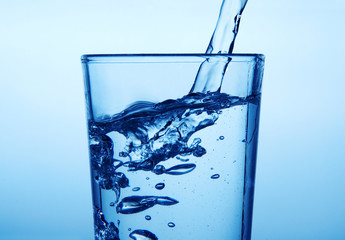 Pouring milk into glass with blue background