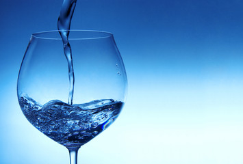 Pouring milk into glass with blue background