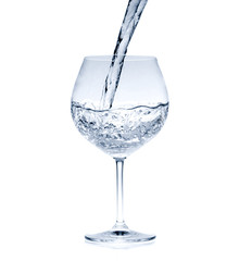 Pouring water into glass isolated on white