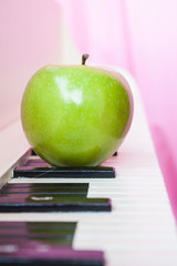 Green apple on piano, Pink color background