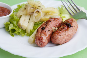 Appetizing fried sausages with a tomato sauce and a fried potato