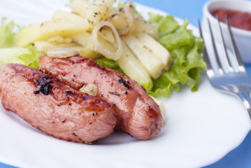 Appetizing fried sausages with a tomato sauce and a fried potato