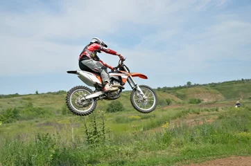 Tuinposter Motocross rider on a motorcycle in a jump © VVKSAM