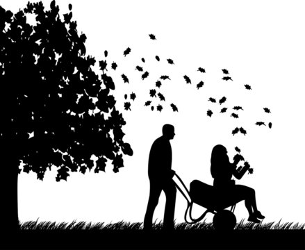 Man pushing a girl in cart in autumn or fall silhouette