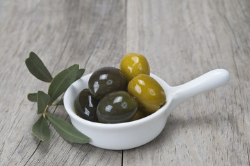 Aperitivo de aceitunas en cuchara de china y fondo de madera.