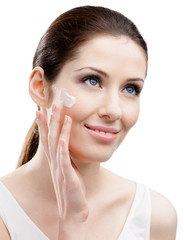 Woman applying cream on her face, isolated on white
