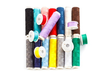 Several multicolored bobbins and coils with sewing thread