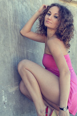Obraz na płótnie Canvas Fashionable beautiful curly brunette model in pink dress posing