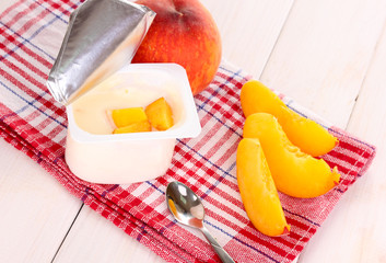 Yogurt with peach on wooden background