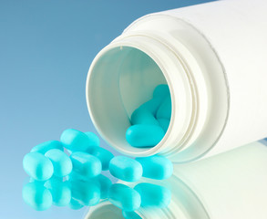 Capsules in bottle, on blue background