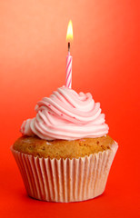 tasty birthday cupcake with candle, on red background