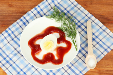 Boiled egg with ketchup on wooden background