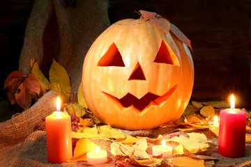 halloween pumpkin and autumn leaves, on wooden background