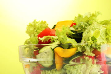 fresh vegetable salad in transparent bowl on green background