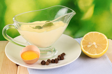 Mayonnaise in bowl on wooden table on nature background