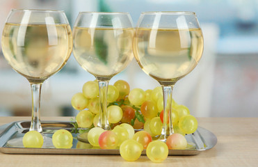 White wine in glass on salver on room background