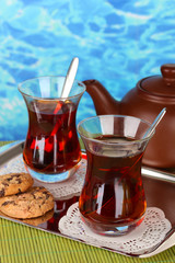 glass of Turkish tea and kettle on color background