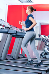 Fototapeta na wymiar Młoda kobieta na siłowni uruchomić na na maszynie