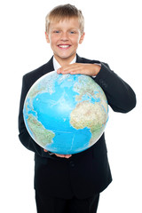 Cheerful boy in suit holding globe with both hands