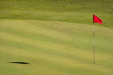 Obraz premium Golf course with red flag in the hole