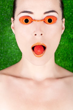 Woman Wearing Tanning Bed Glasses With Strawberry In Mouth