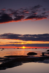 Naklejka premium Beautiful sunset at sea, large rocks in foreground
