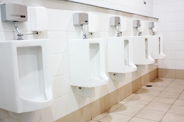 row of white toilets in a man restroom