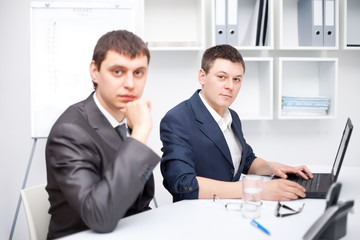 Two young businessmen working together in office