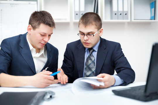 Two young businessmen working together in office