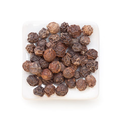 Black pepper (Piper nigrum) in a white bowl on white background.