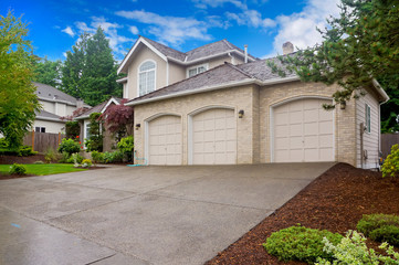 Large beige house with three car garage and large driveway.