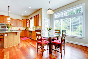 Dining room and kitchen with red cherry wood and large window.