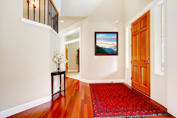 Large home luxury entrance with red rug and wood door.