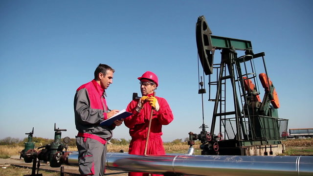 Two Workers in front of Oil Well