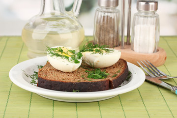 Boiled eggs  on dark bread on green background