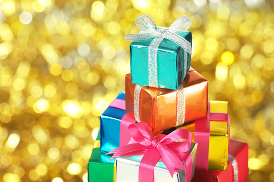 Pile Of Small Gifts On Gold Blurry Lights Background.(horizontal