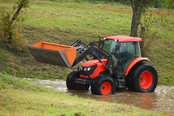 Obraz premium Tractor repair of rural roads, which flooded the rain