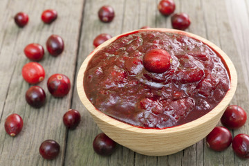 Cranberries jam in bowl on wooden boards