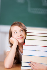 nachdenkliche schülerin mit einem stapel schulbücher