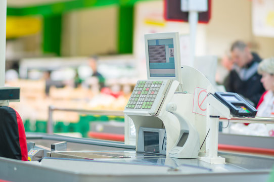 Cash-desk with terminal in supermarket. Customers on background