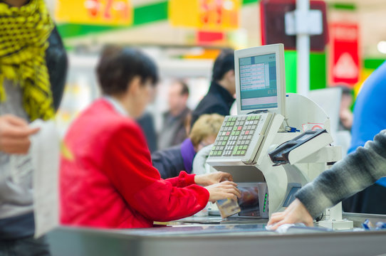 Cash-desk with cashier and terminal in supermarket. Serve custom