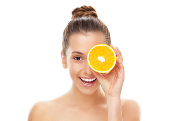 Woman holding orange over eye