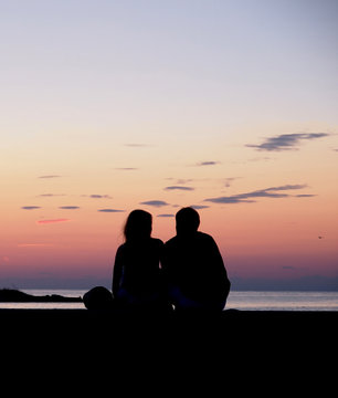Couple watching the sunset by the sea