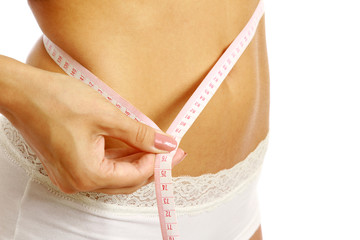 A slim girl measuring her waist, closeup