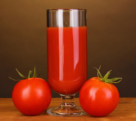 Tomato juice in glass on wooden table on brown background