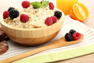 tasty oatmeal with berries and glass of juice, on wooden table